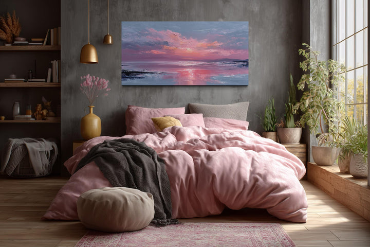 Blush pink ocean sunset coastal canvas wall art hanging above a bed in a modern bedroom.