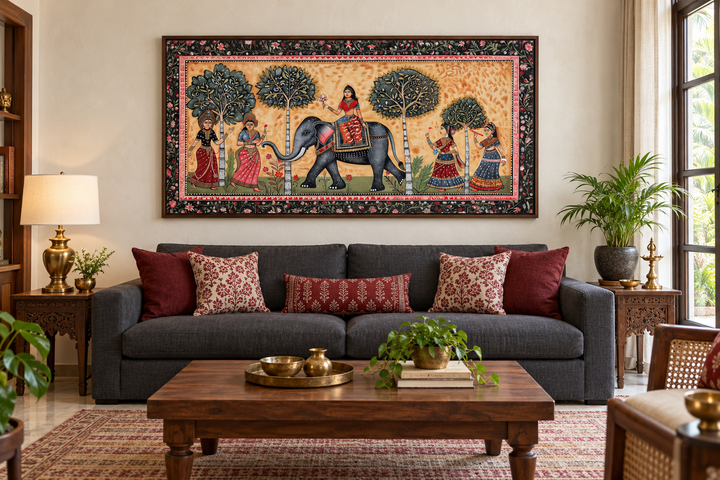 Framed Madhubani style canvas wall art of an Indian elephant and women above a dark grey sofa.