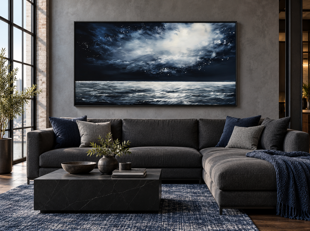 Dark horizontal starry night ocean seascape framed canvas wall art above a gray sectional sofa.