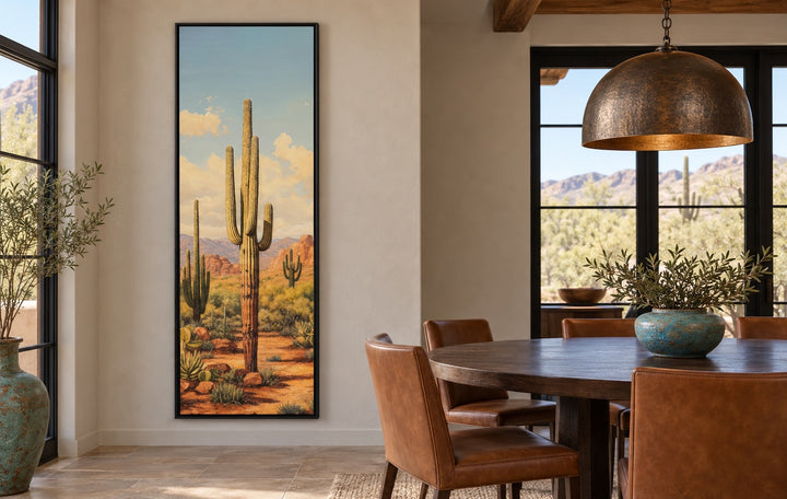 Tall vertical saguaro cactus canvas wall art in a black frame on a neutral dining room wall.