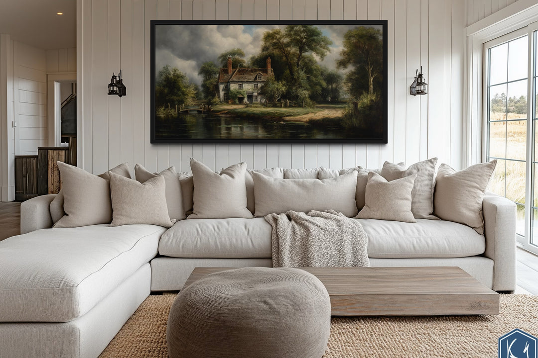 a large, white sectional sofa with multiple pillows, a wooden coffee table, and a large painting of a countryside landscape hanging on the wall above the sofa.