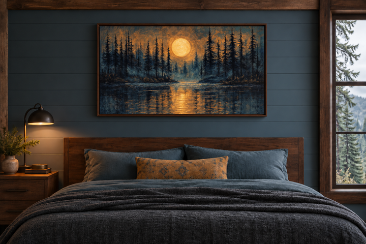 Moody moon over pine forest and lake at night wall art in a walnut frame above a bed.