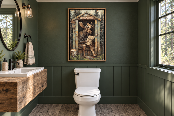 Moose in outhouse reading newspaper wall art in a green rustic bathroom above a white toilet.