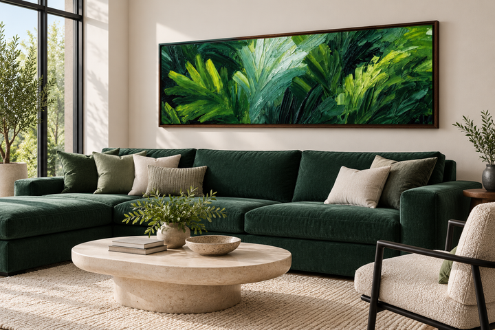 Long horizontal canvas print of lush green rainforest leaves above a dark green sectional sofa.