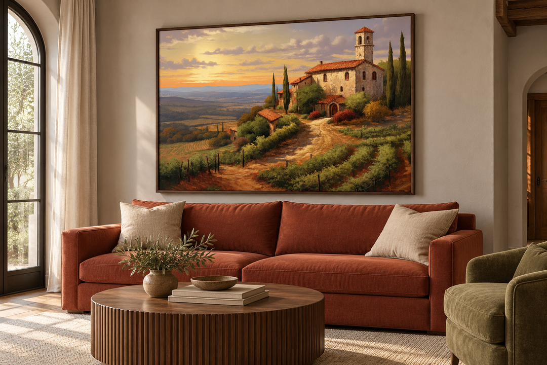 Framed canvas wall art of a Tuscan landscape with a stone villa above a terracotta sofa.