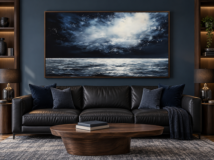 Dark horizontal starry night ocean seascape framed canvas wall art above a black leather sofa.