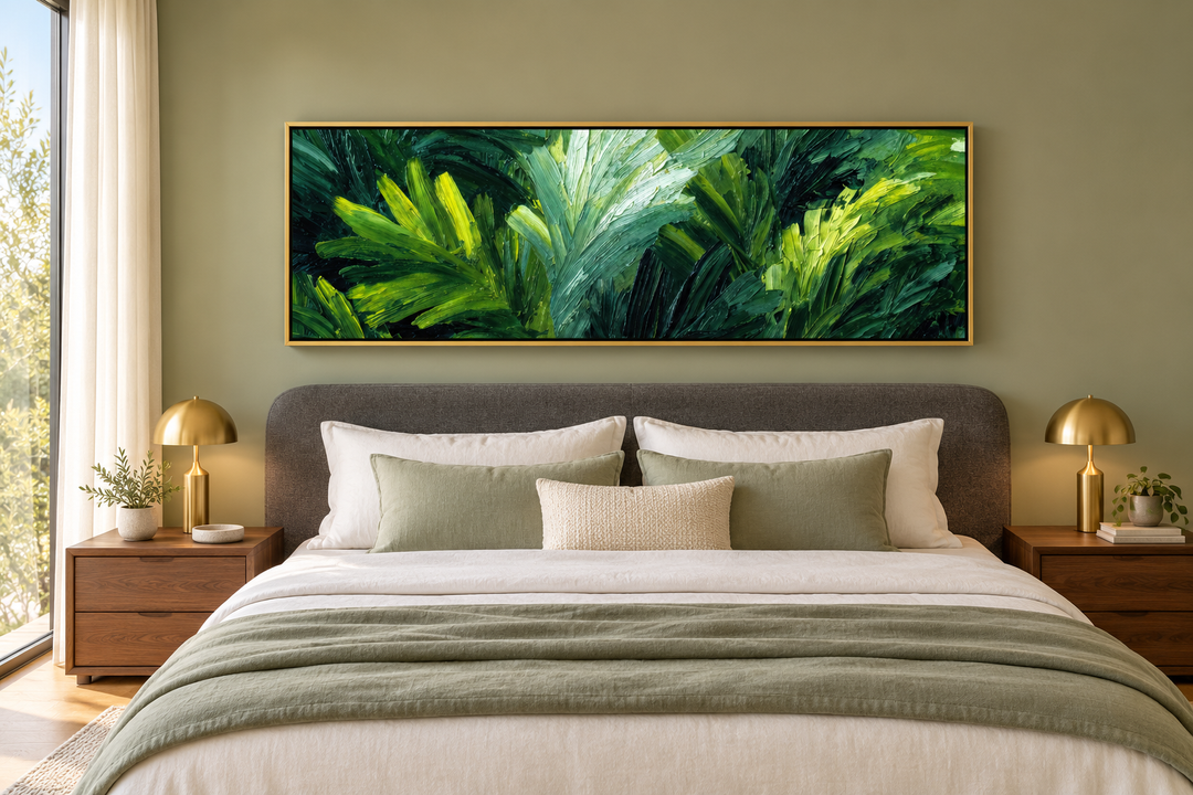 Panoramic rainforest jungle leaves canvas print in a gold frame above a bed in a green bedroom.