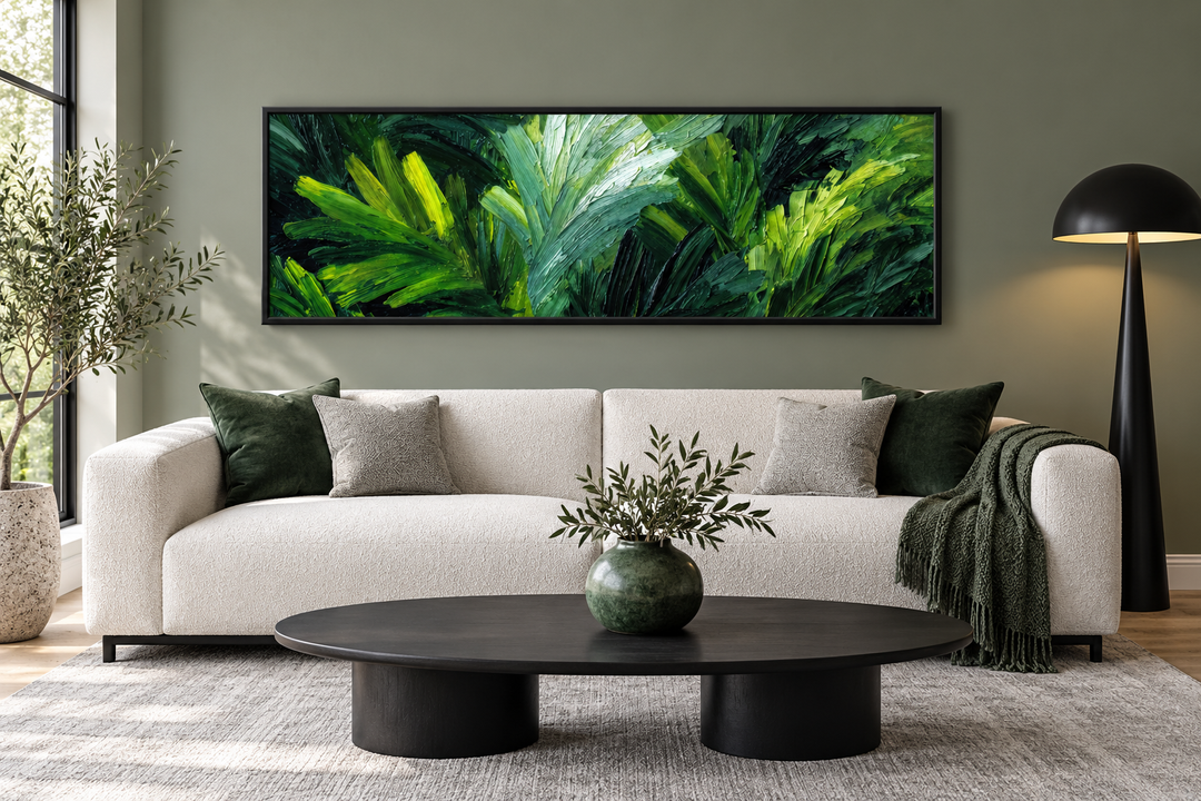 Panoramic rainforest jungle leaves wall art in a black frame above a modern ivory sofa.
