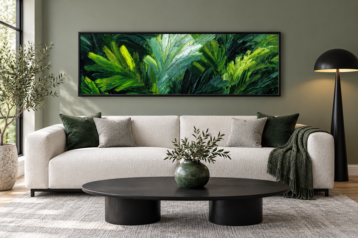 Panoramic rainforest jungle leaves wall art in a black frame above a modern ivory sofa.
