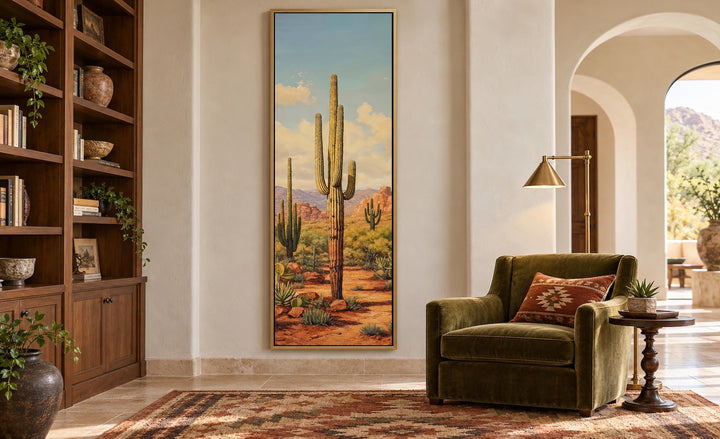 Tall vertical saguaro cactus canvas wall art in a gold frame on a neutral wall in a living room.