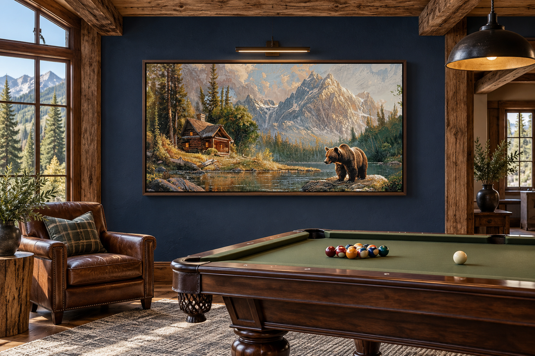 Framed panoramic canvas art of a bear near a mountain cabin by a lake in a rustic billiards room.