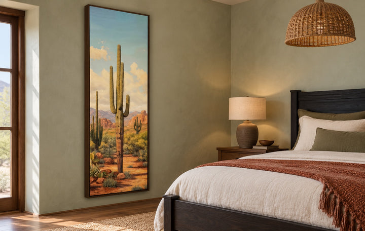 Tall vertical saguaro cactus canvas wall art in a walnut frame on a sage green bedroom wall.