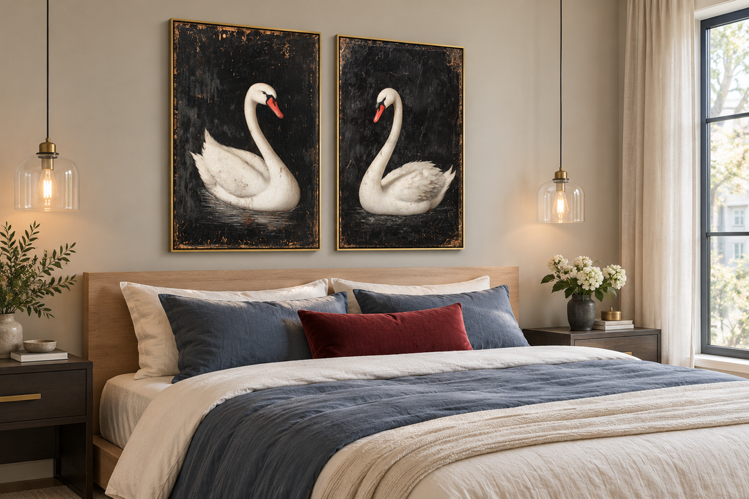 Set of 2 framed canvas wall art featuring antique white swans on a black background above a bed.