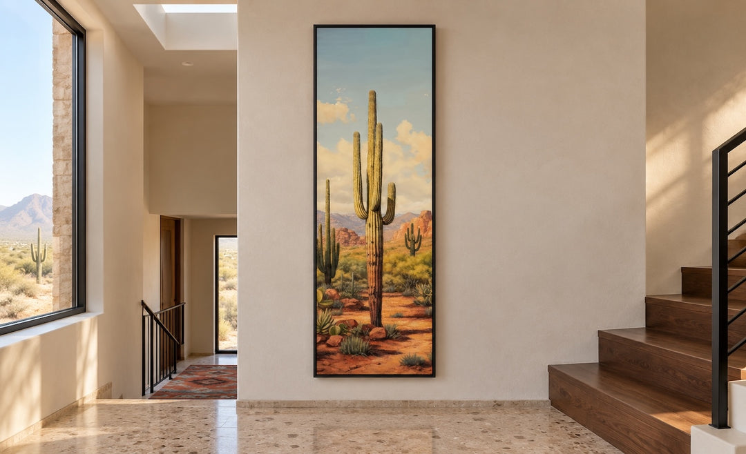 Tall vertical saguaro cactus canvas wall art in a black frame on a neutral hallway wall.