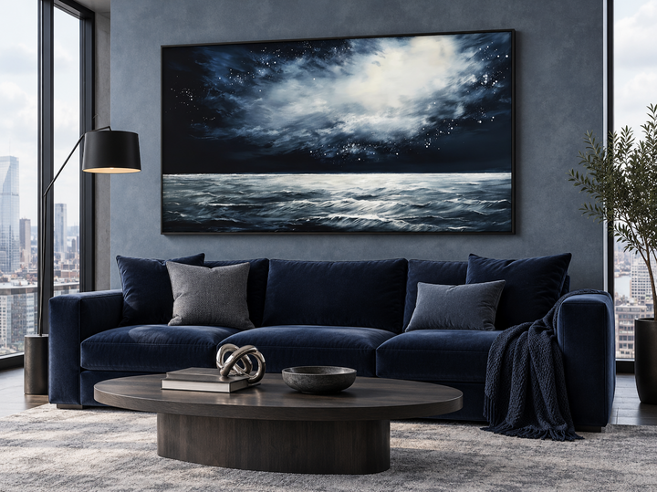 Dark horizontal framed canvas wall art of a starry night over a moody ocean in a modern living room.