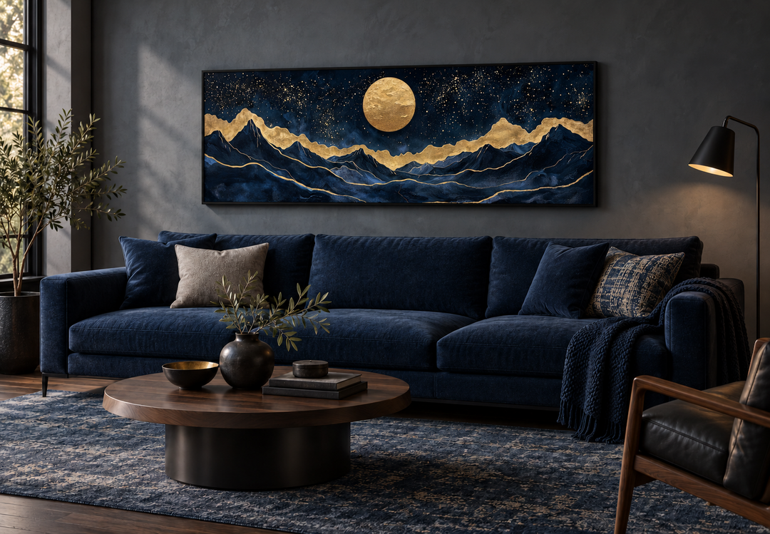 Gold and navy moon mountain landscape canvas print above a blue velvet sofa in a modern living room.