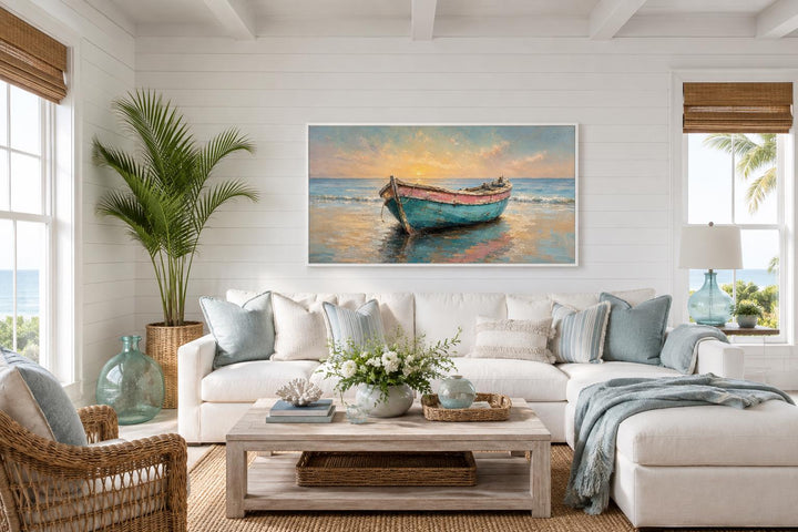 Weathered teal and pink rowboat painting on a coastal living room wall at golden sunset.