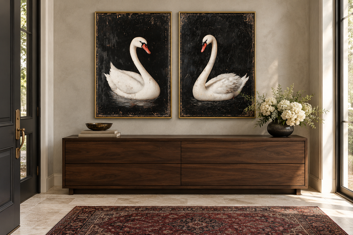 Set of 2 framed canvas prints featuring white swans on a black background above a wooden sideboard.