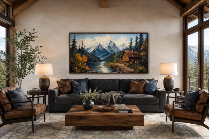 Mountain cabin on the river vintage style canvas wall art hanging above a dark gray sofa.