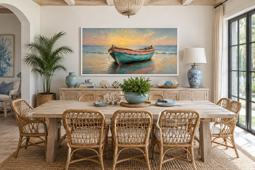 Weathered teal and pink rowboat on a shore at sunset, coastal wall art in a light dining room.