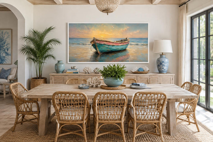 Weathered teal and pink rowboat on a shore at sunset, coastal wall art in a light dining room.