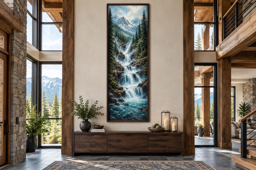 Tall narrow canvas art of a cascading mountain waterfall through a pine forest with snowy peaks.