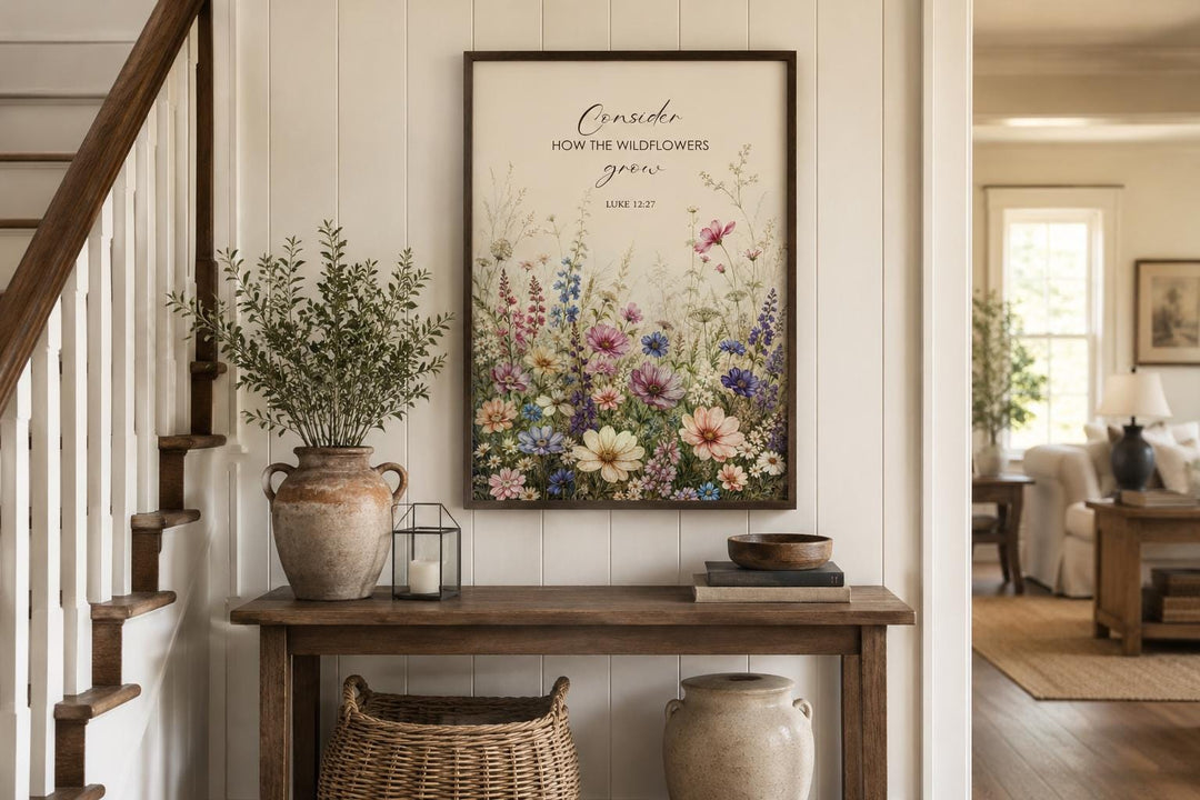 Wildflower watercolor wall art with Luke 12:27 scripture verse in a dark wood frame on a white wall.