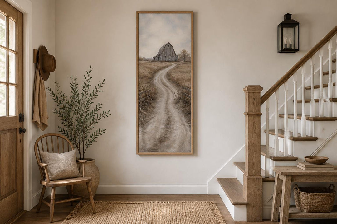 Tall narrow farmhouse wall art of a weathered barn and winding road in an entryway setting.