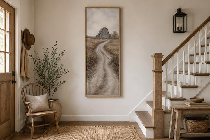 Tall narrow farmhouse wall art of a weathered barn and winding road in an entryway setting.