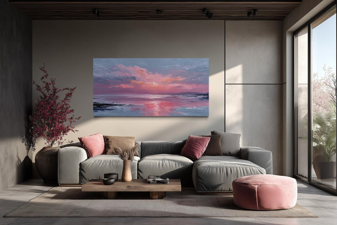 Blush pink ocean sunset coastal canvas wall art displayed above a modern grey sectional sofa.