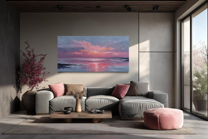 Blush pink ocean sunset coastal canvas wall art displayed above a modern grey sectional sofa.