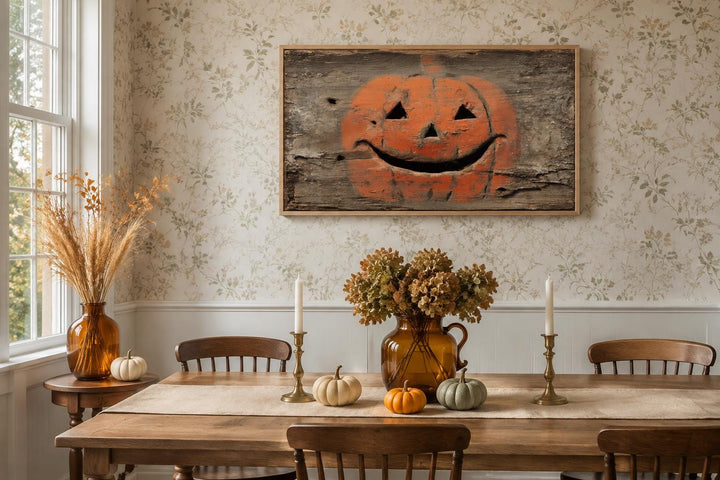 Primitive jack-o'-lantern canvas wall art on weathered wood background in a rustic dining room.