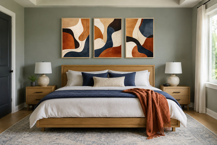 3 piece mid-century modern abstract wall art in earth tones, brown, cream, and navy above a bed.
