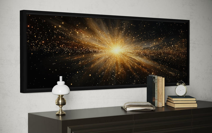 A wide black framed canvas featuring a radiant gold starburst explosion on a dark background.