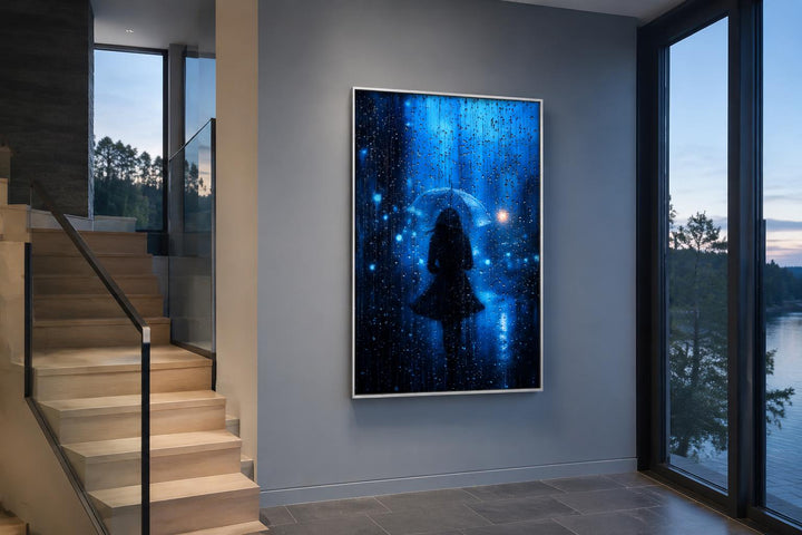 Vertical canvas wall art of a woman's silhouette with an umbrella in blue rain on a gray wall.