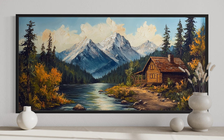 Vintage style canvas wall art of a log cabin by a river with snow-capped mountains in the background