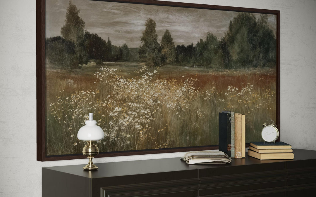 Framed canvas wall art of a neutral wildflower meadow landscape above a dark wood dresser.