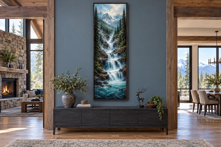 Tall narrow canvas art of a cascading mountain waterfall through a pine forest with snowy peaks.