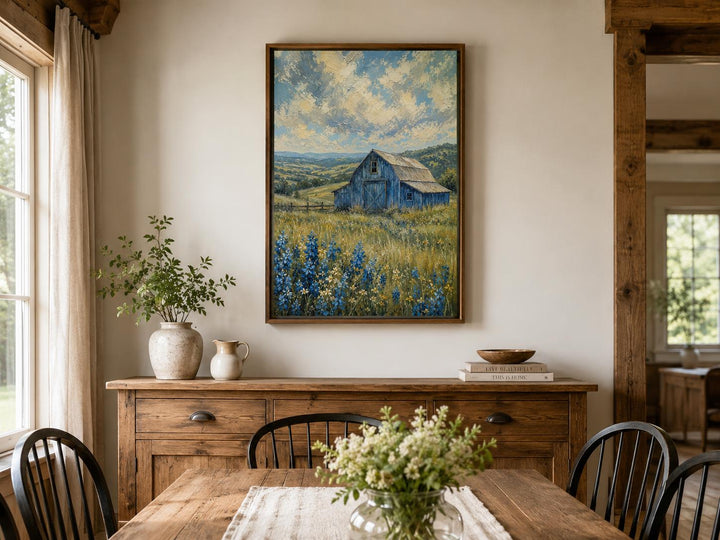 Vertical canvas art of a blue barn in a field of bluebonnets under a cloudy sky in a wood frame.