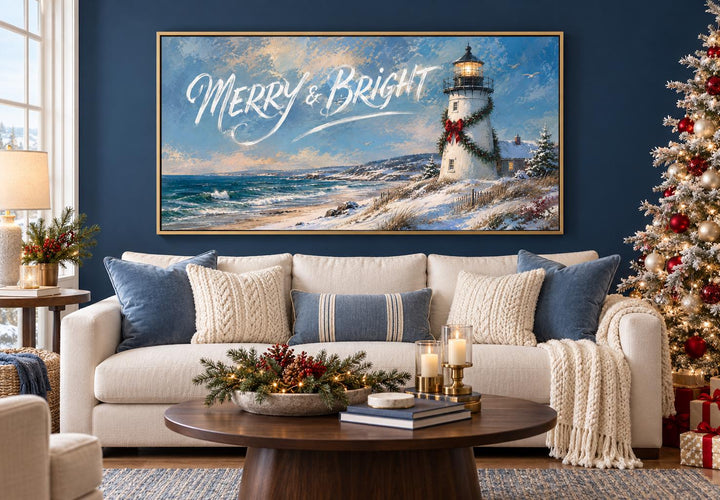 Merry & Bright coastal Christmas lighthouse framed canvas wall art above a sofa in a living room.