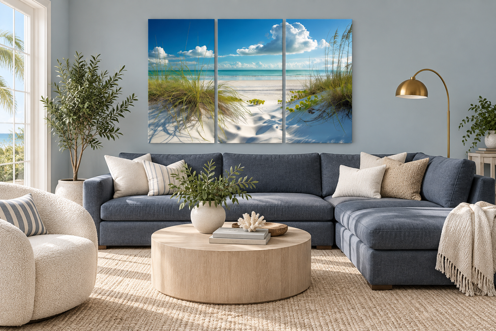5-piece canvas wall art of a white sand beach with sea grass dunes above a blue sectional sofa.