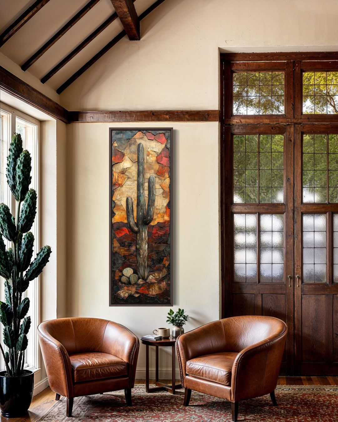 Vertical tall narrow saguaro cactus wall art in a rustic living room with leather chairs.