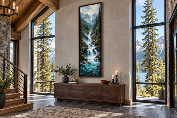Tall narrow canvas wall art of a cascading mountain waterfall through a pine forest with snow peaks.
