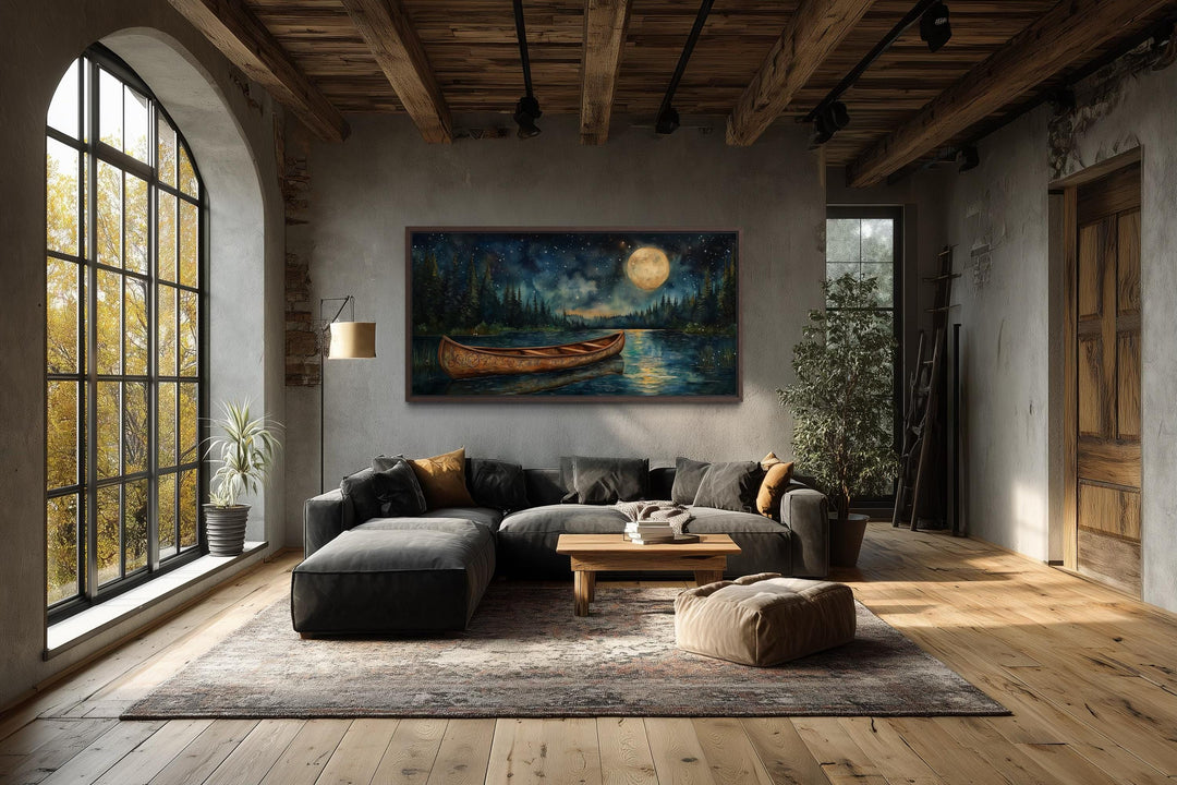 Canoe on moonlit lake and forest night scene canvas wall art hanging in a rustic living room.