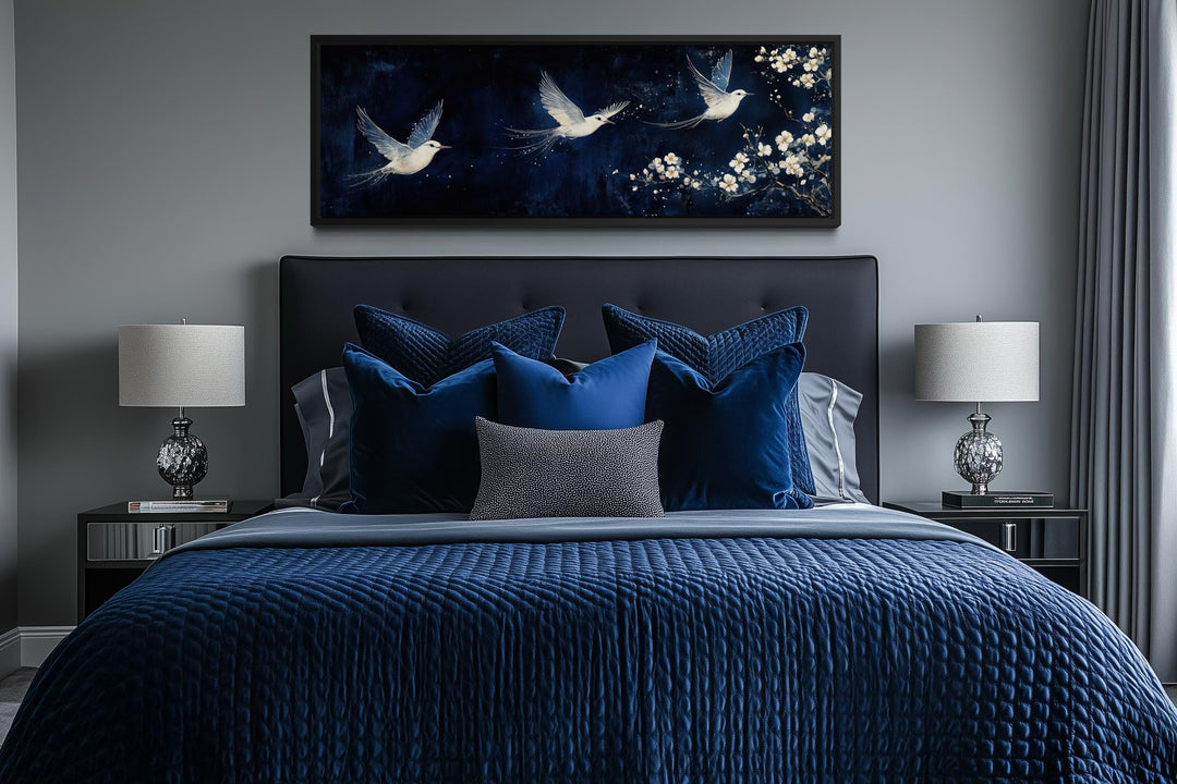White birds on navy background long narrow wall art above a bed with navy blue bedding.
