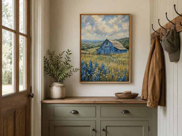 Vertical canvas art of a blue barn in a field of bluebonnets under a cloudy sky in a wood frame.