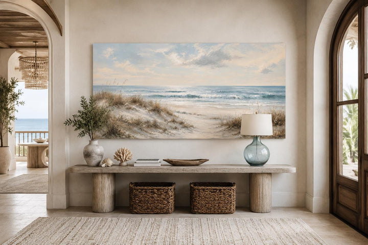 Sandy beach dunes wall art with sea grass and rolling waves in a coastal living room setting.