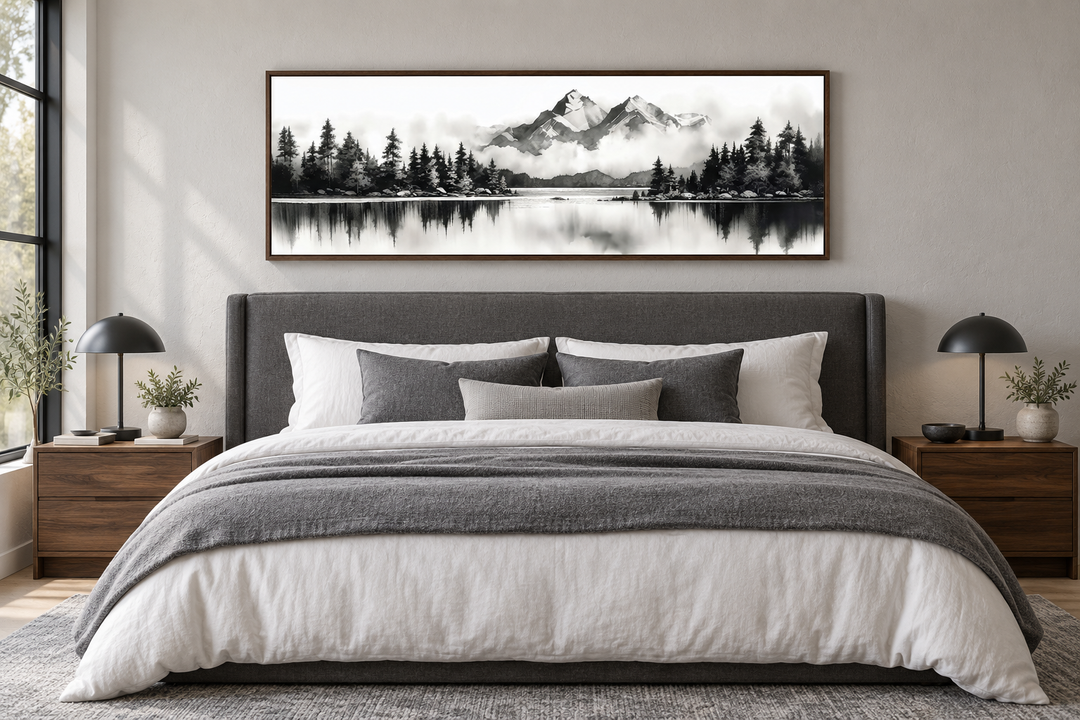 Black and white narrow canvas wall art of a mountain lake landscape hanging above a bed.