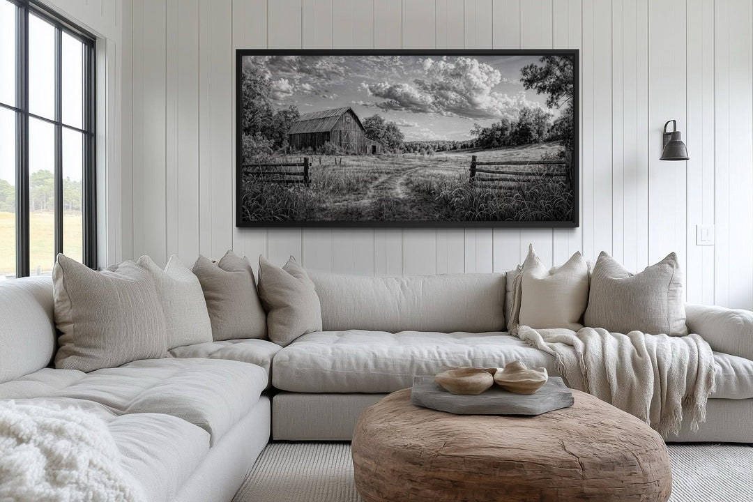 Black and white barn landscape canvas wall art hanging above a neutral sectional sofa.