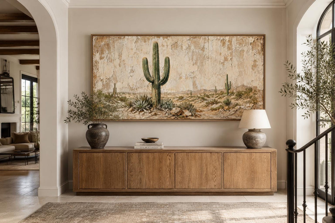 Minimalist saguaro cactus canvas wall art on a weathered wood-look background above a wood console.